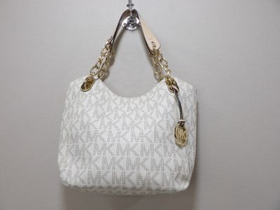 un sac à main Michael Korsh blanc accroché à un crochet fixé au mur
