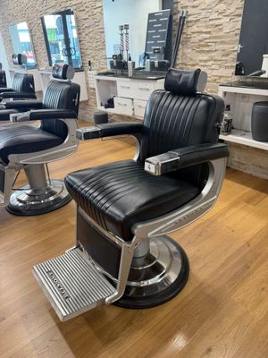 fauteuil de coiffeur noir et chromé devant un mur en pierre