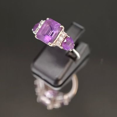 un gros plan d'une bague sertie d'une pierre violette et de diamants