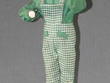 an image of a doll is standing on a wooden block