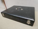 une valise noire posée sur une table, avec une bague dessus