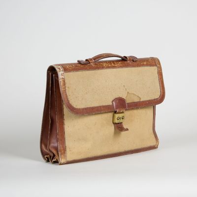 une mallette marron et beige posée sur une surface blanche