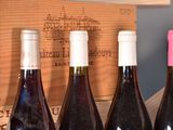 several bottles of wine are lined up in a row in front of a wooden box