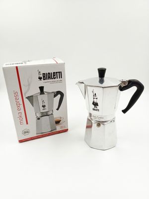 une petite cafetière posée à côté d'une boîte de café