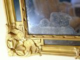 a gold frame with a mirror on it that is hanging on the wall