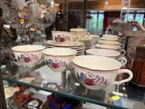 many cups and saucers sitting on a glass shelf