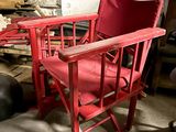 a red chair sitting in a room with a pile of firewood