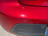 a close up of a red car with a blue license plate on it