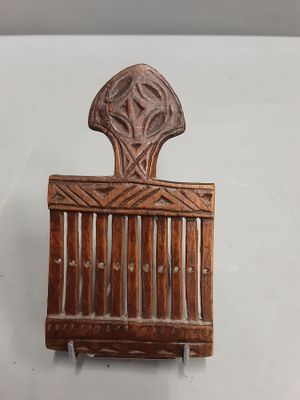 un vieux peigne en bois est posé sur une surface blanche