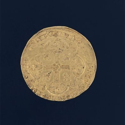 an old gold coin with a cross on it on a black background