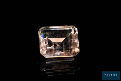 a pink diamond on a black surface with a black background