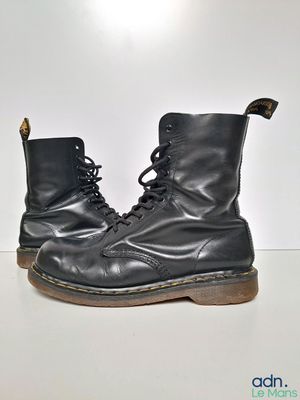 une paire de bottes en cuir noir posées sur une surface blanche, avec un fond blanc