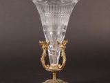 an antique glass vase on a gold stand on a black background