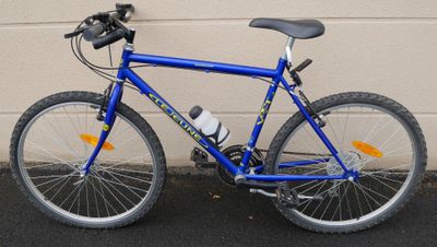 un vélo bleu garé devant un immeuble