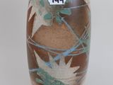 a brown vase with leaves on it on a white surface