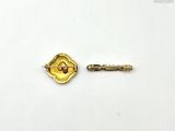 a gold pin and a small gold pin on a white surface