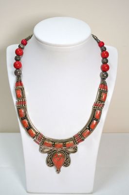 une photo d'un collier avec des perles rouges porté par un mannequin