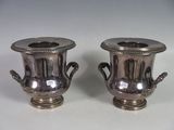 two silver vases that are sitting on a table