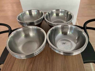 four stainless steel bowls sitting on top of a wooden table