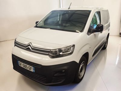 La camionnette blanche est garée dans une grande pièce au sol blanc.