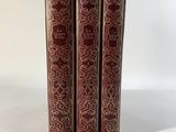 trois livres rouges superposés sur une surface blanche