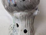 a white vase with a bird on it sitting on a table