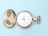 a silver pocket watch with a picture of a woman on it