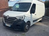 La camionnette blanche est garée sur le parking, à côté d'un bâtiment en briques.