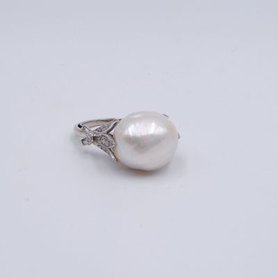 une bague en perle blanche et diamants posée sur une surface blanche