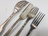 three forks and a knife on a white table