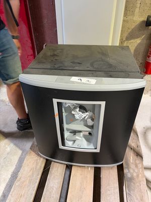 un réfrigérateur noir et argent posé sur une palette en bois