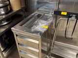 une table en acier inoxydable avec un plateau en verre dans une cuisine