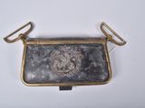 un vieux sac à main orné d'un lion, posé sur une surface blanche