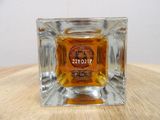a small glass candle holder with a bottle of liquor in it