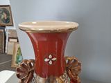 a red vase sitting on a table with pictures in the background