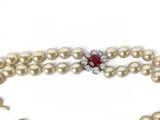 a pearl necklace with a red stone surrounded by pearls