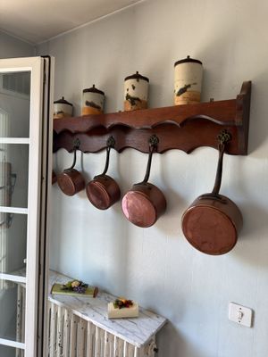 pots and pans are hanging on a rack in a kitchen