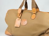 beige and tan handbag with leather handles on a white background