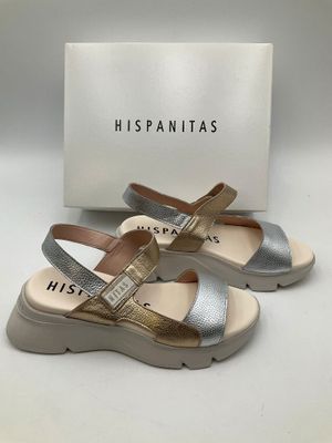 une paire de sandales argentées et dorées, avec une boîte en arrière-plan