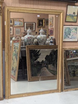 un grand miroir au milieu d'une pièce dont les murs sont ornés de tableaux