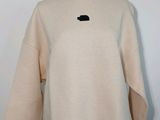 un pull blanc avec un patch noir sur la poitrine