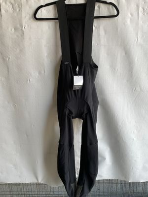 black bib shorts hanging on a hanger on a white wall