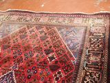 an image of a red rug on a wooden floor with a cat sitting on top of it