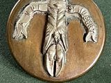 un badge métallique sur lequel figure l'image d'un homme