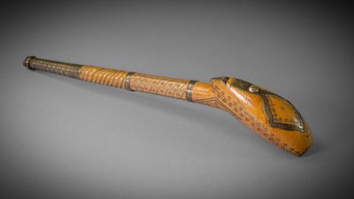 une vieille pipe sur laquelle sont gravés des caractères, posée sur une table