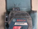 Le niveau laser Bosch Professional est posé par terre à côté du sac à outils.