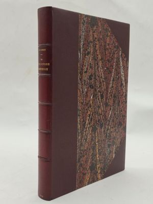 un vieux livre à la couverture rouge posé sur une surface blanche