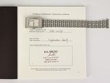 a silver watch on top of a black book