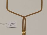 gros plan d'un collier en or sur une surface blanche