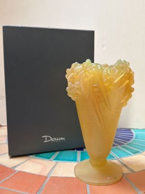 un vase jaune posé sur un sol carrelé, à côté d'une boîte noire